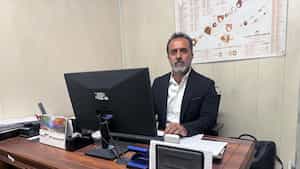 کارشناس ارشد فنی پشت میز کار، با نمودار فنی روی دیوار